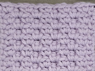 Close-up of lavender yarn worked in the Staggered Block Mesh Stitch with offset groups of Single Crochet stitches.