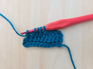 Four partially completed Double Crochet stitches on the hook before being completed together.