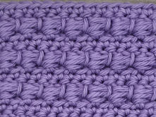 Close-up of purple yarn crocheted in the Bead stitch, showing raised wrapped stitch clusters arranged in horizontal rows.