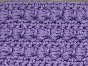 Close-up of purple yarn crocheted in the Bead stitch, showing raised wrapped stitch clusters arranged in horizontal rows.