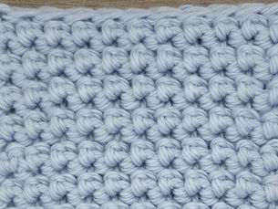 Close-up of light blue yarn crocheted in the Rug stitch, showing compact rows of raised rounded stitches.