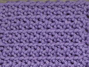 Close-up of purple yarn crocheted in the Swirl stitch, showing staggered Single Crochet stitches separated by raised horizontal rows.
