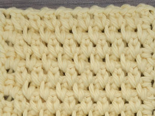 Close-up of yarn worked in the Counterpane Stitch with staggered chain one openings.