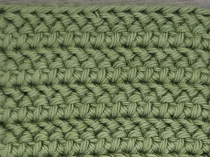 Close-up of yarn worked in rows of slanted Herringbone Half Double Crochet stitches.