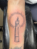 Tattoo of a burning candle with radiating light on an arm