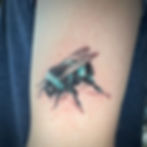 Blue and black bee tattoo on arm