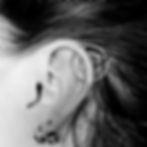 Black and white ear with industrial and lobe piercings