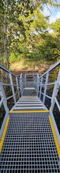 Outdoor grp access stairs with yellow strips leading into woods