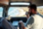 digital nomad sipping on coffee from their van while working on laptop. nomad lifestyle luxuries.