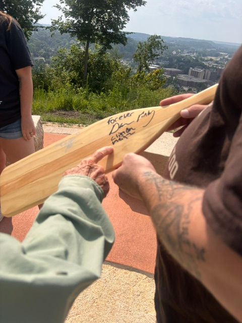 The "boys" signing their name on the back of the paddle.