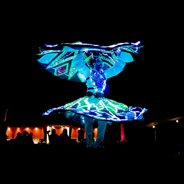 Professional folk artist performing hypnotic, spinning Tanoura heritage dance show inside traditional Bedouin desert camp