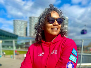 Open water swimmer in red hoodie with sub10 club swim badges looking happy