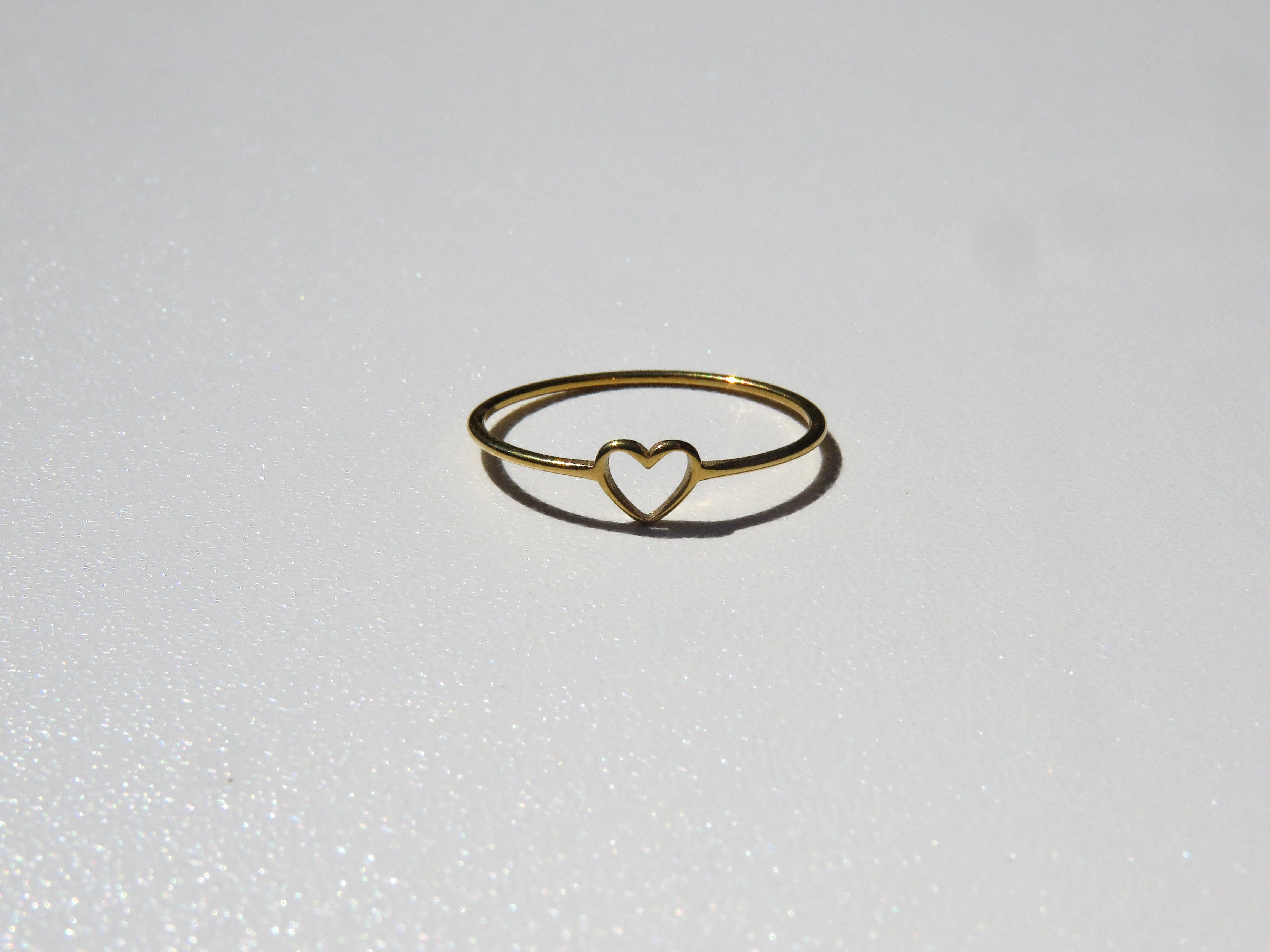 Gold ring with tiny open heart in the middle on a white background