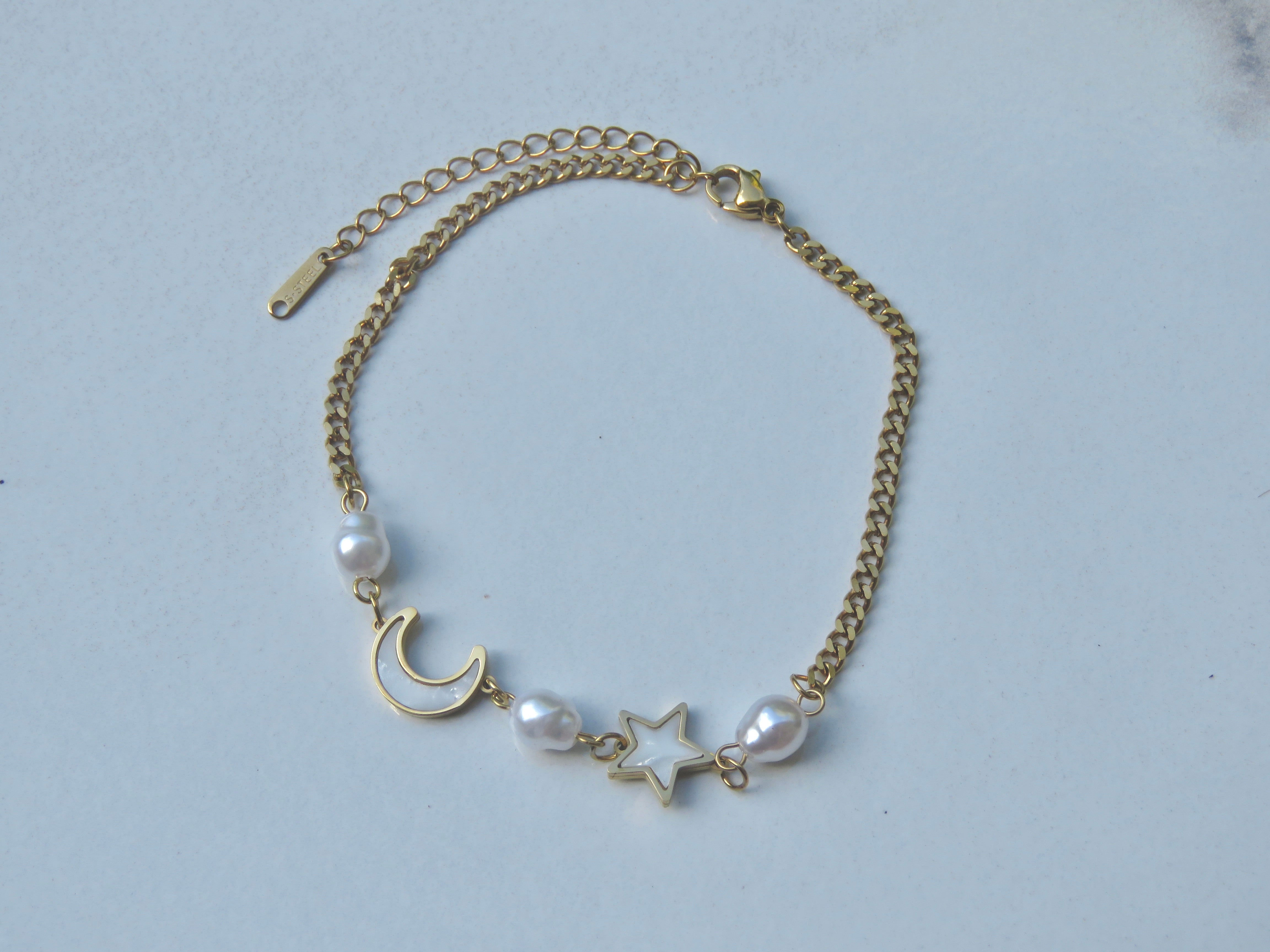 Gold anklet with white faux pearls, moon and star charms with extender on white background