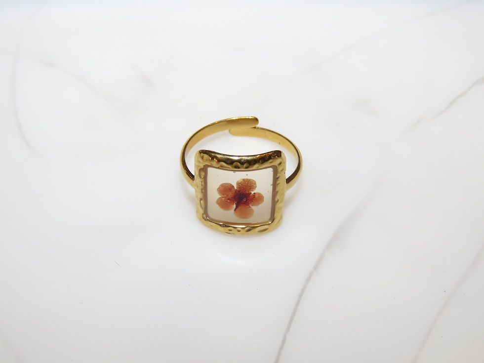 Tiny flower encased on a gold frame ring