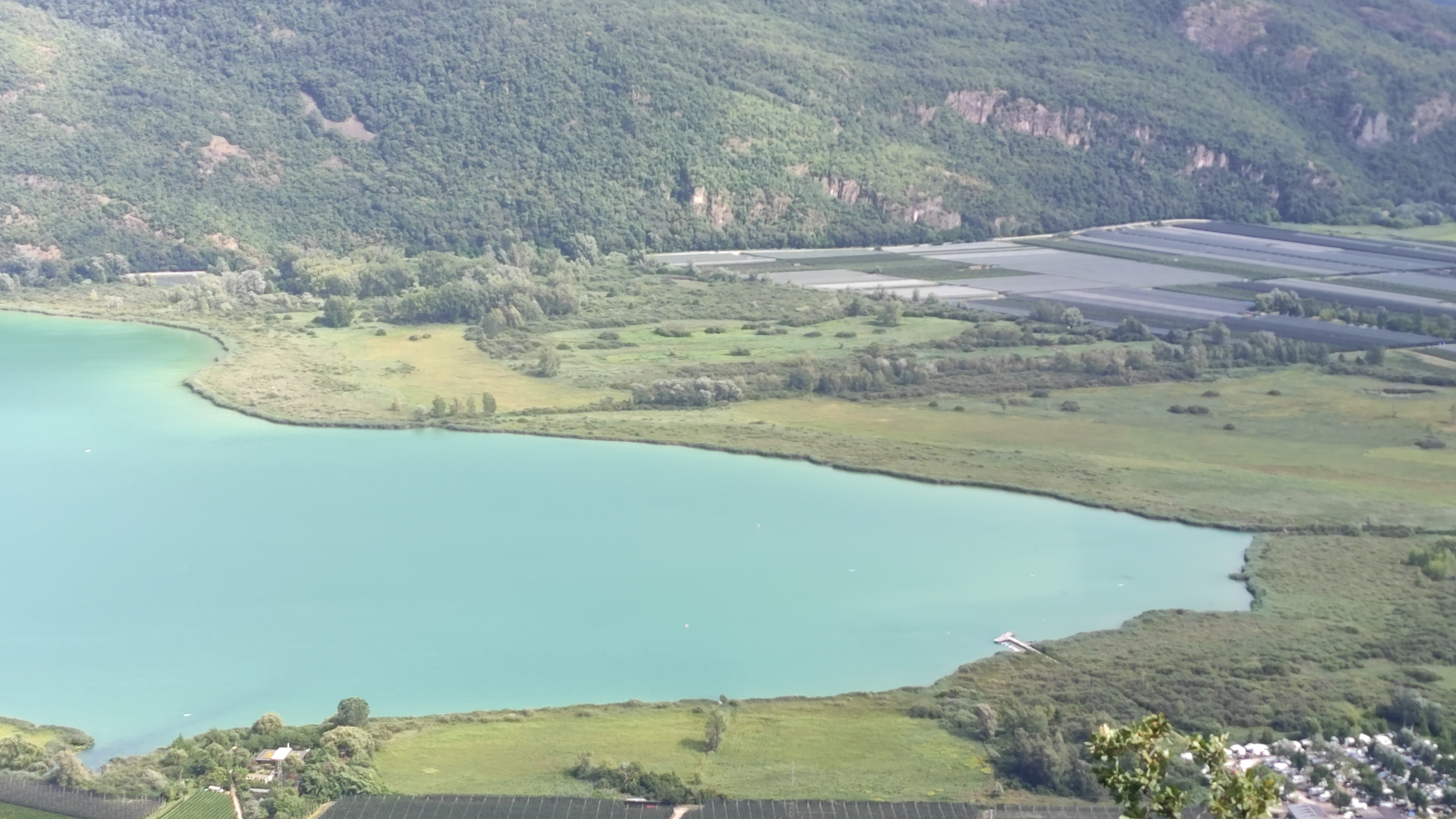 Le lac de Caldaro, dans le paysage d’implantation de Ritterhof — Boboseiptu, Wikimedia Commons, CC BY-SA 4.0. Seconde image : régions, lieux viticoles et cépages de la maison.