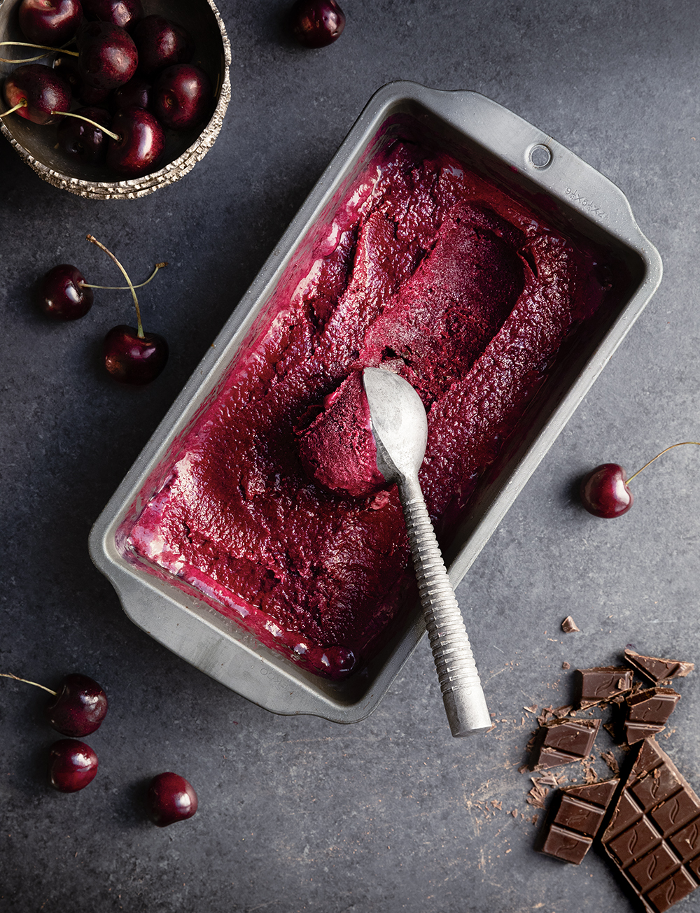 Cherry sorbet in a metal container with ice cream scoop