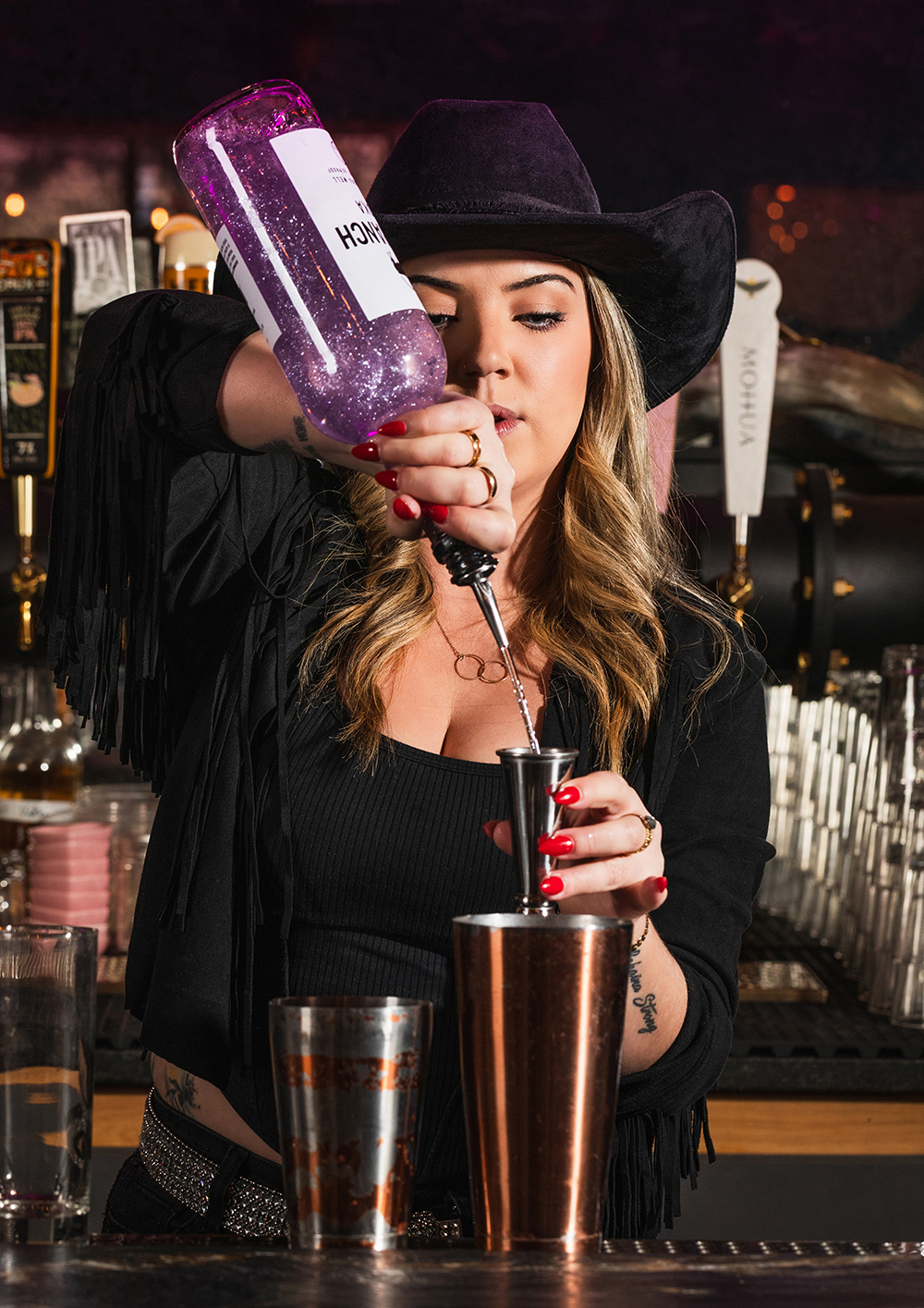 Female bartender with cowboy hat pouring drink