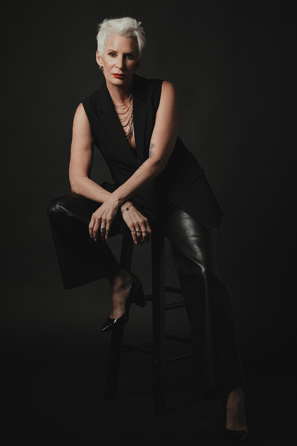 Older woman in black clothes sitting on stool