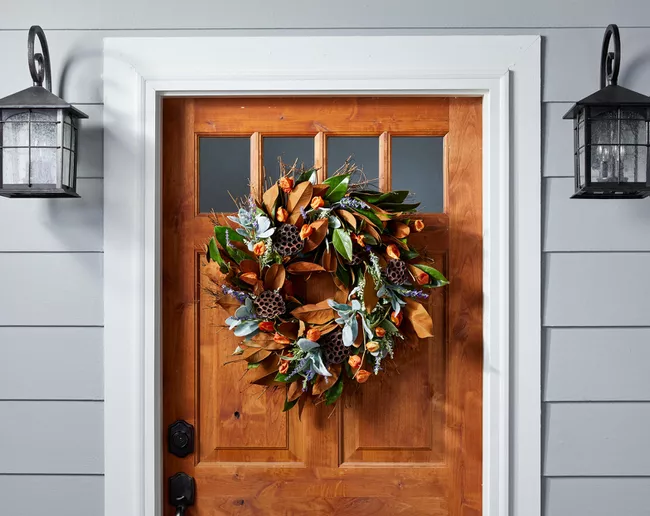 If you want to be crafty and creative with decorating, this idea is for you! Pull out a glue gun and safely weave dried flowers, leaves, and branches into a wreath form. Begin with the larger items and follow with the thinner items on top. Next, wire dried fruit with floral wire by wrapping it around the wreath to give a stunning finishing touch to your beautiful front door accessory. But, in case you’re not a crafty expert, no need to worry. You can simply scour through some nearby stores and find an affordable and ready-made flower wreath.