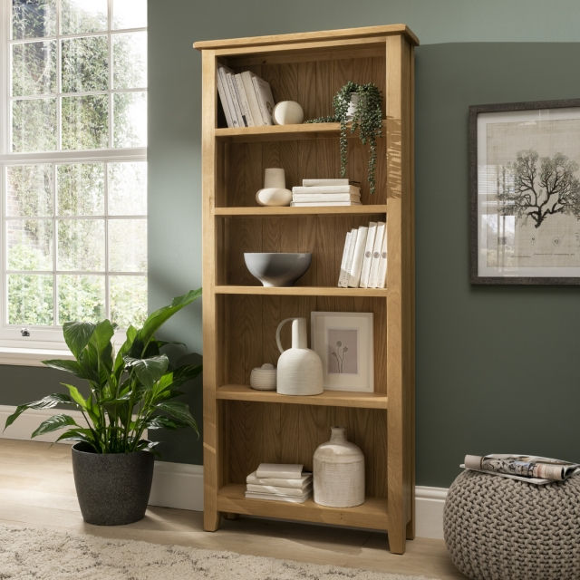 Bookshelves offer another way to vertically guide the eye. By adding vertical decorative panels on the length of your walls, your eye continues moving toward the ceiling, which helps create visual height. Therefore, tall, skinny bookshelves extending up to the ceiling can create an illusion of a higher ceiling and wider space. This innovative storage method also proves to be a replacement for messy piles against walls and allows you to organise important books and papers in a way that gives a roomier impression. Be sure to style the bookshelf nicely — here are our top tips on how to do so!