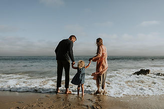 Couple and child walking along the beach, representing connection, relationships and family.