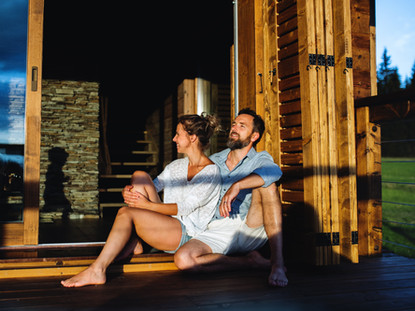 happy-couple-sitting-on-patio-of-wooden-cabin-holi-RMHD25H.jpg