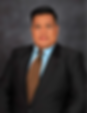 Man in a suit with a blue shirt and brown tie, posed against a gray background. He has a neutral expression, providing a formal mood.