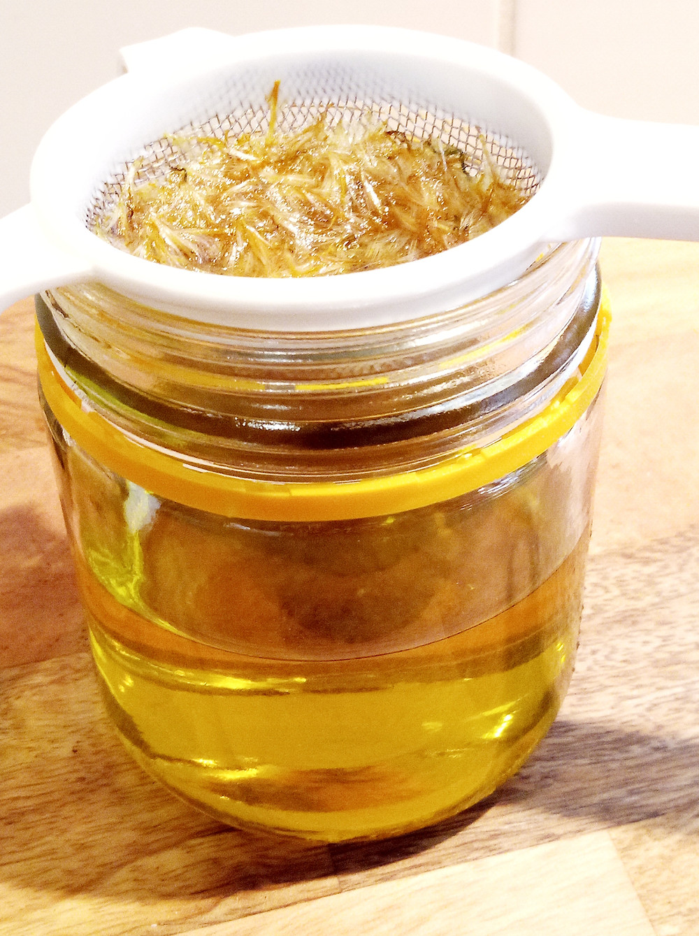 straining flowers out of infused oil