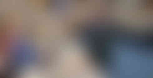 A Cub Scouts stands at the library desk checking out some books with a librarian