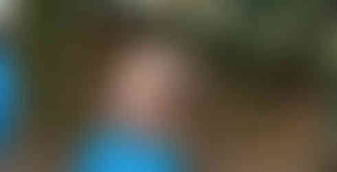 A Beaver Scout excitedly holds up their stick with bread dough wrapped around the top