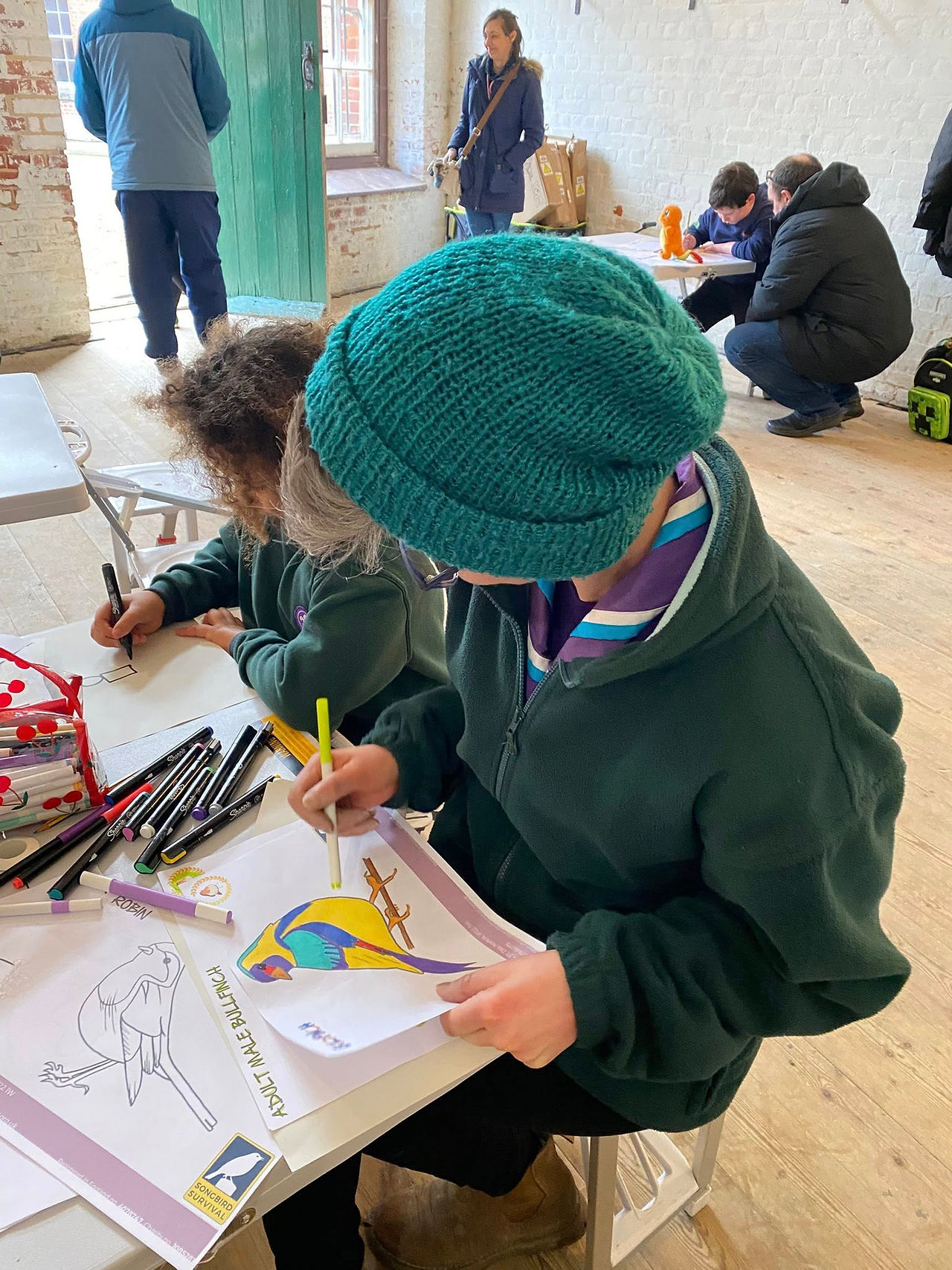 A Cub Scout sits with an adult at a table colouring
