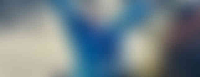 A Beaver Scout sits inside a self-propelled car on a children's ride, their head is back and they have their arms outstretched while smiling widely