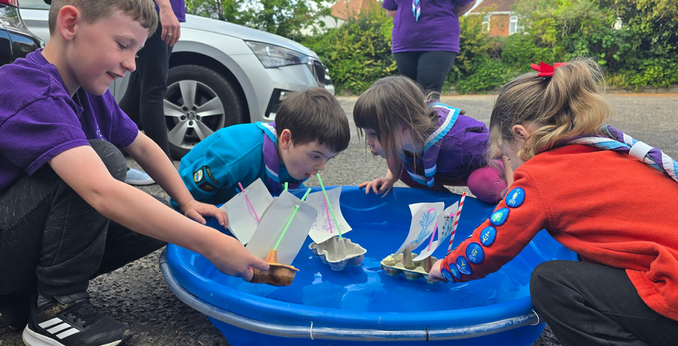 Squirrel and Beaver Scouts put boats made of egg cartons, straws and paper into a small plastic paddling pool and attempt to blow them around to make them sail