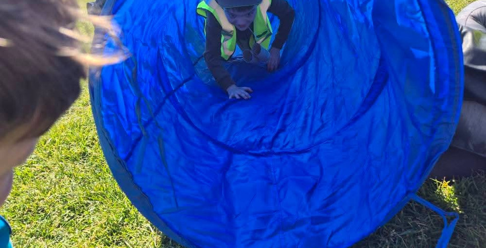 A Beaver Scout crawls through a play tunnel