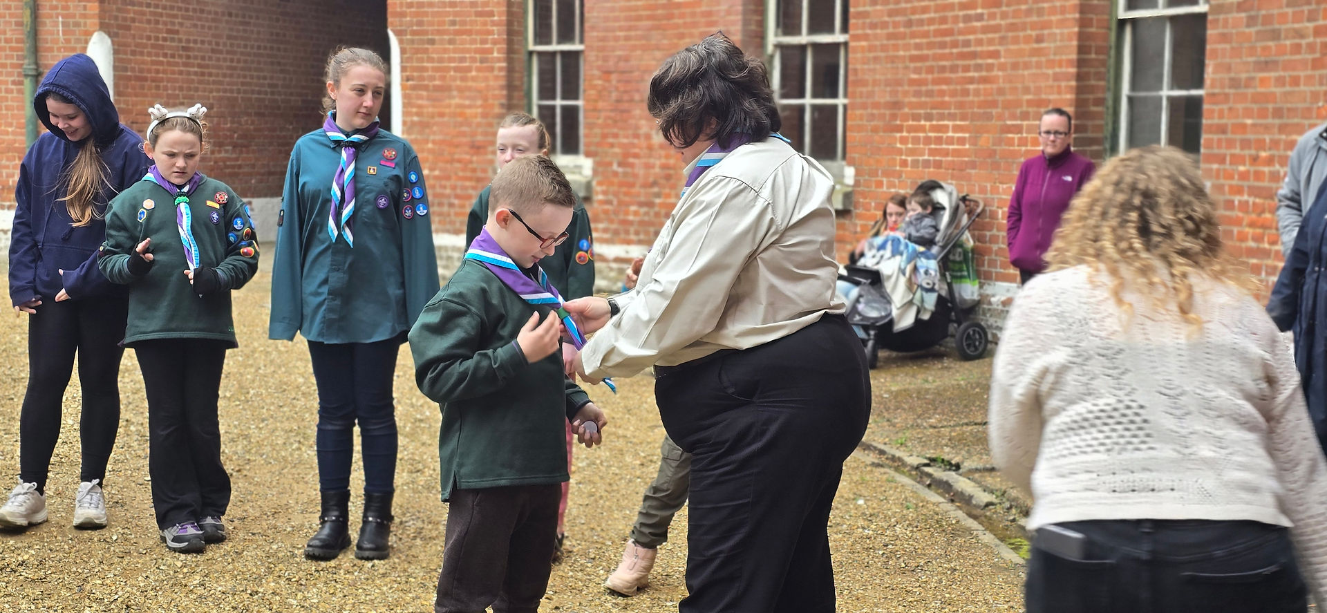 A Cub has his neckerchief put on by his leader