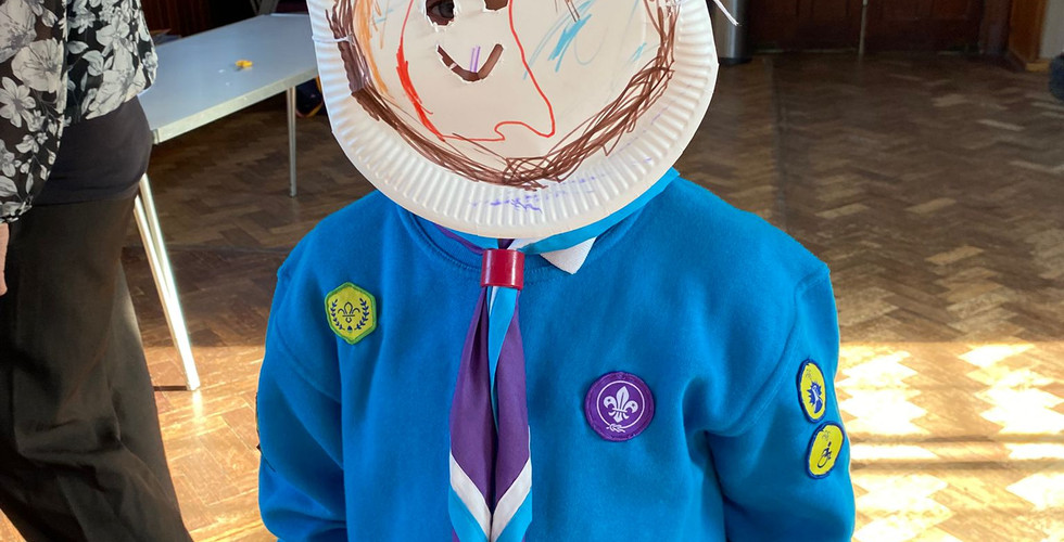 A Beaver Scout wears a paper plate mask he's created