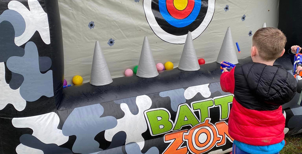 A Beaver Scout aims a nerf gun at an inflatable target booth