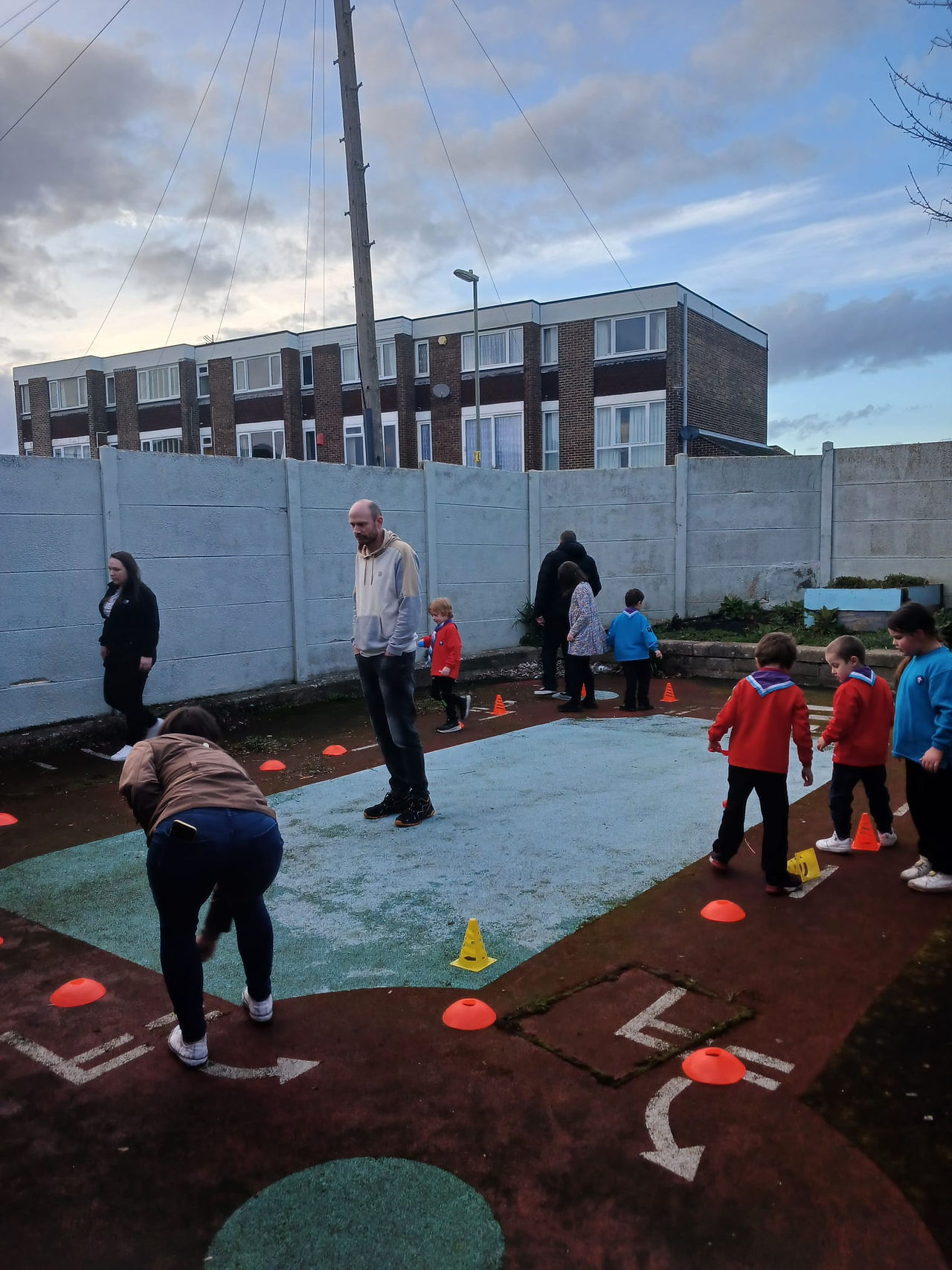 Squirrel and Beaver Scouts play egg and spoon races in an outside space with adults. There are markers and cones on the floor