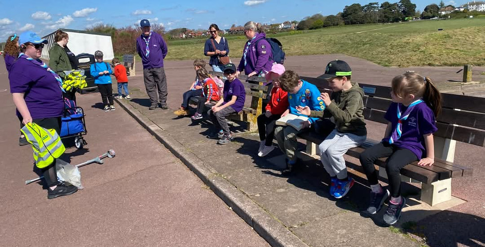 Squirrel and Beaver Scouts sit with adults on benches