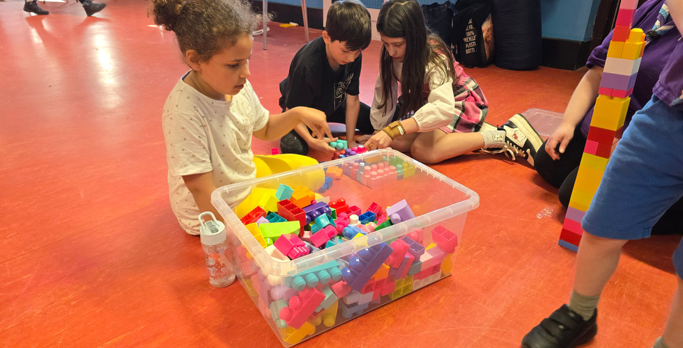 Cubs and a Scout sit around a large box of Mega Blocks (large chunky construction blocks)