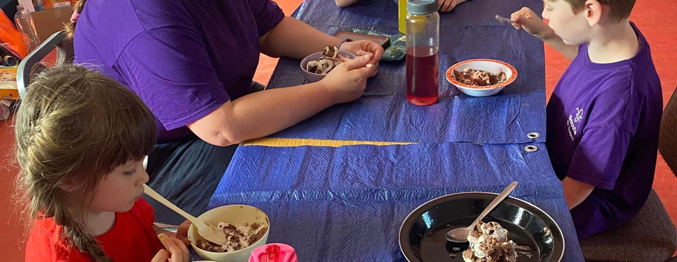 Three Squirrel Scouts sit at a table with a leader with bowls of ice cream