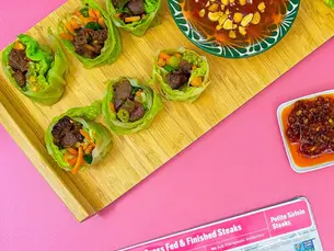 6 cabbage rolls on a cutting board with a spicy sauce and pre petite sirloin nearby.