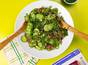 An overhead shot of a cucumber salad with sesame seeds, chili peper, and seaweed and kimchi, with Pre 95% lean ground beef in a package nearby.