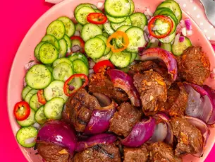 Plate of kabobs and cucumbers with red onion.