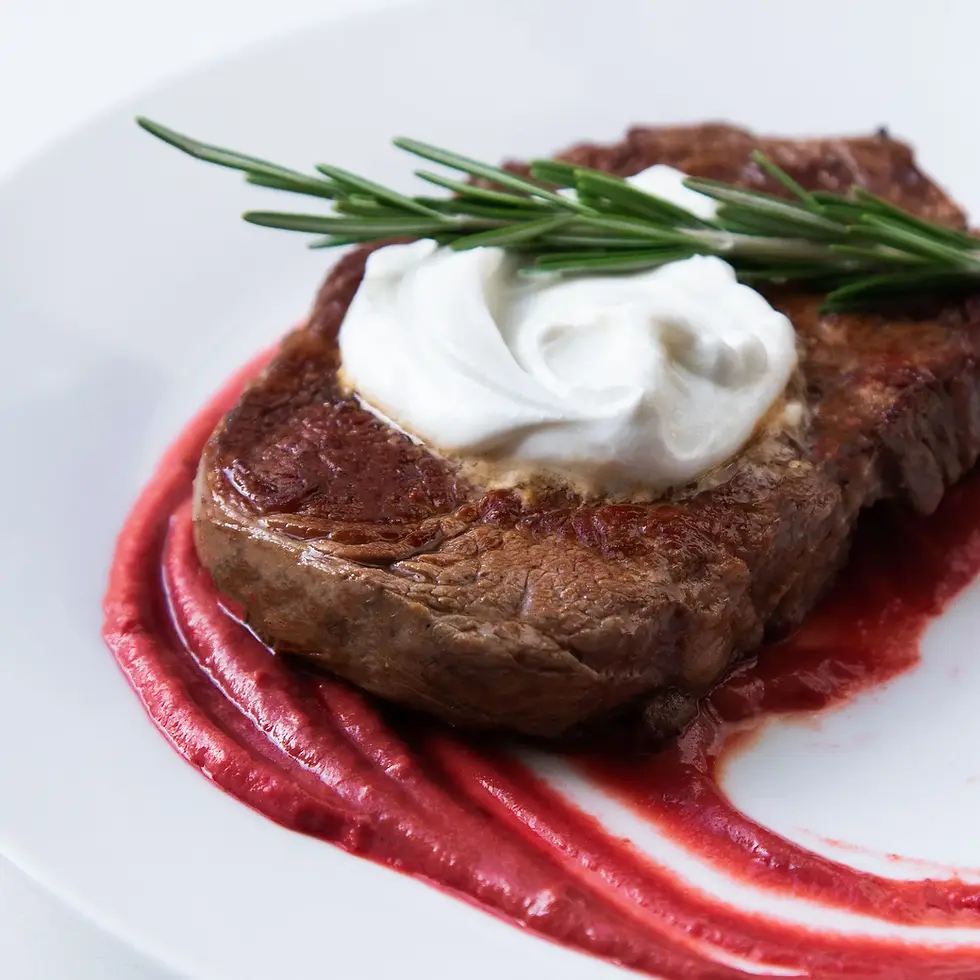 A ribeye steak on a bed of beet pureé and topped with whipped chévre