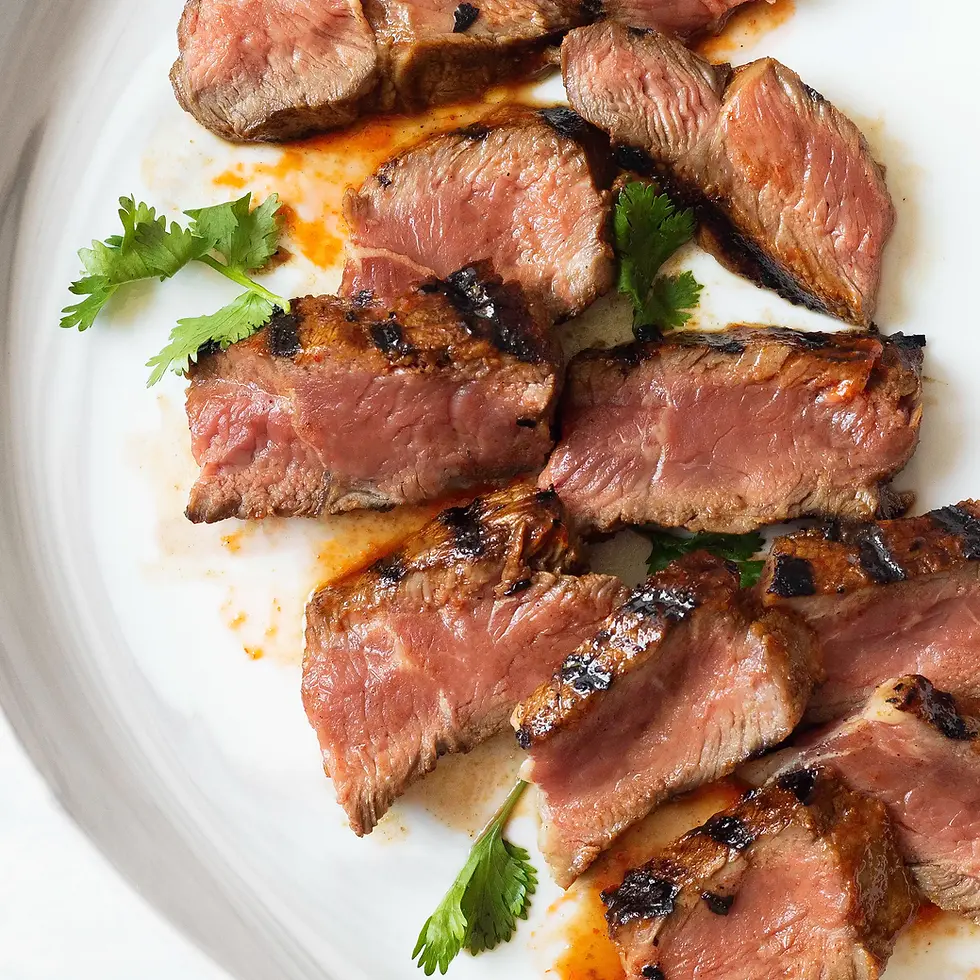 A plate of NY strip steak with marinade on the grilled pieces.