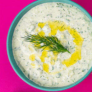 Overhead shot of  bowl of white creamy sauce with a swirl of olive oil and bits of dill mixed in, with a drill frond in the center.