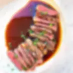 A sliced steak on a plate with A.1. sauce around it