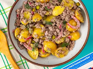 An overhead shot of potato salad in a large bowl neary a package of Pre 92% Lean Ground Beef.